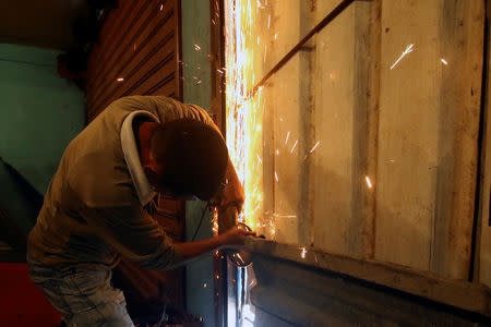 A worker repairs the gate of a mini-market after it was looted in San Felix, Venezuela January 24, 2019. REUTERS/William Urdaneta