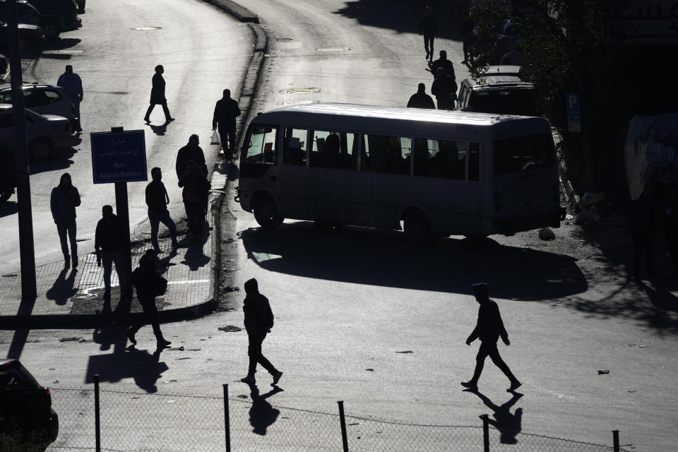 People are silhouetted on the streets as vehicles block a main roadway during a general strike by public transport unions protesting the country's deteriorating economic and financial conditions in Beirut, Lebanon, Wednesday, Feb. 2, 2022. (AP Photo/Hassan Ammar)