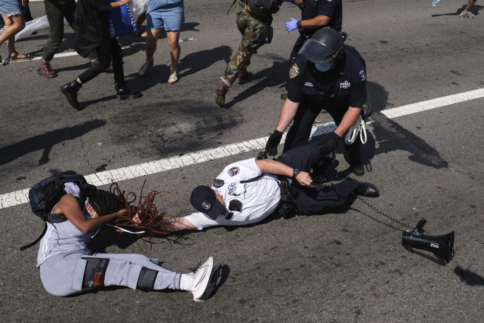 A Black Lives Matter protester and NYPD officers scuffle on the Brooklyn Bridge during a demonstration, Wednesday, July 15, 2020, in New York. Several New York City police officers were attacked and injured Wednesday on the Brooklyn Bridge during a protest sparked by the death of George Floyd, police said. At least four officers were hurt, including the department’s chief, and more than a dozen people were arrested. (AP Photo/Yuki Iwamura)