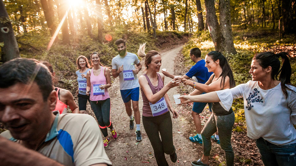 Volunteers handing water to runners in a race