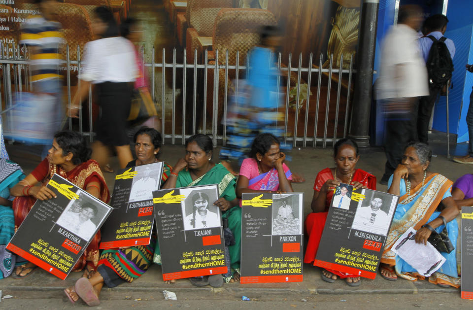 In this Monday, April 6, 2015, file photo, Sri Lankan ethnic Tamil women sit holding placards with portraits of their missing relatives as they protest outside a railway station in Colombo, Sri Lanka. Sri Lanka's president has decided that tens of thousands of people still missing from the country's quarter-century civil war will be formally declared dead and death certificates will be issued, his office said Monday. (AP Photo/Eranga Jayawardena)