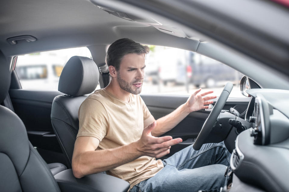 Man sitting at wheel of car gesturing in frustration. Source: Getty Images