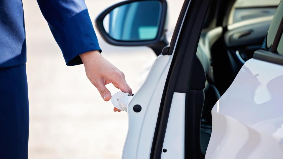 Young businessman opening white car door.