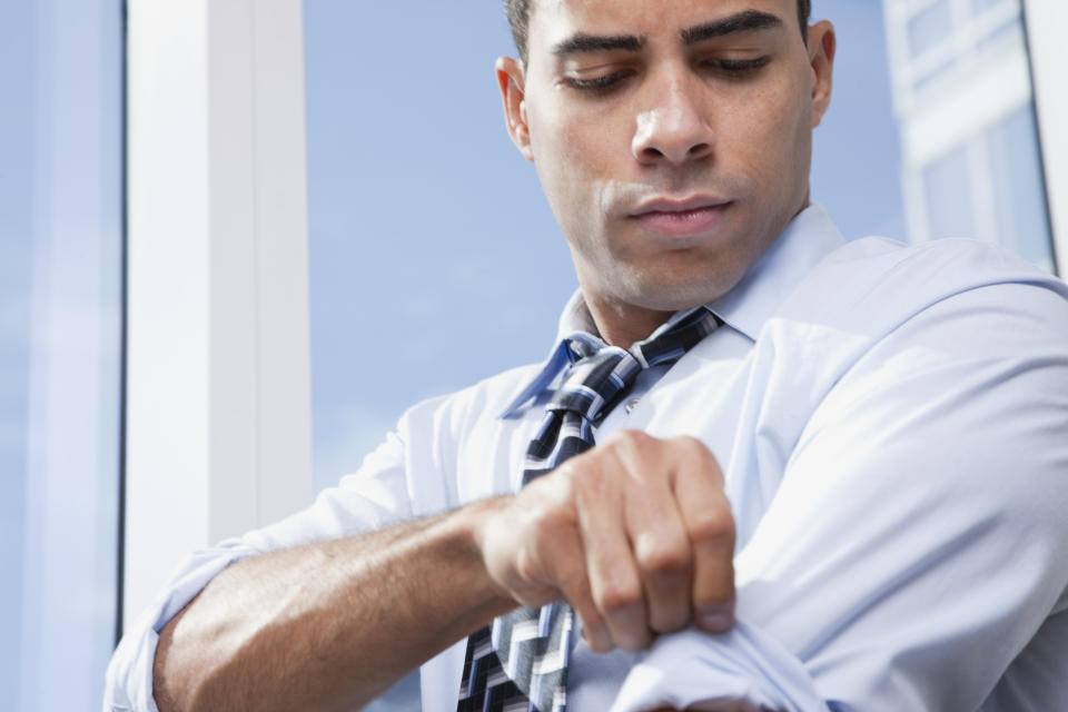 Man wearing suit rolling up sleeves. (Getty Images)