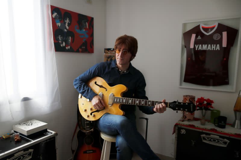 Javier Parisi, who impersonates late former Beatle John Lennon, plays the guitar during an interview with Reuters, in Lanus, on the outskirts of Buenos Aires