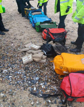 Law enforcement officers stand by holdalls containing cocaine that were washed up on Hopton Beach, near Great Yarmouth, Britain February 9, 2017. Photograph taken February 9, 2017. National Crime Agency/Handout via Reuters