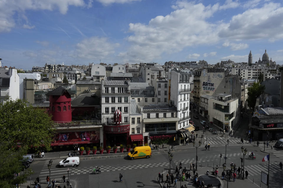 The Moulin Rouge (Red Mill), and the Sacre Coeur basilica, right, are seen Thursday, April 25, 2024 in Paris. The windmill from the Moulin Rouge, the 19th century Parisian cabaret, has fallen off the roof overnight along with some of the letters in its name. (AP Photo/Thibault Camus)