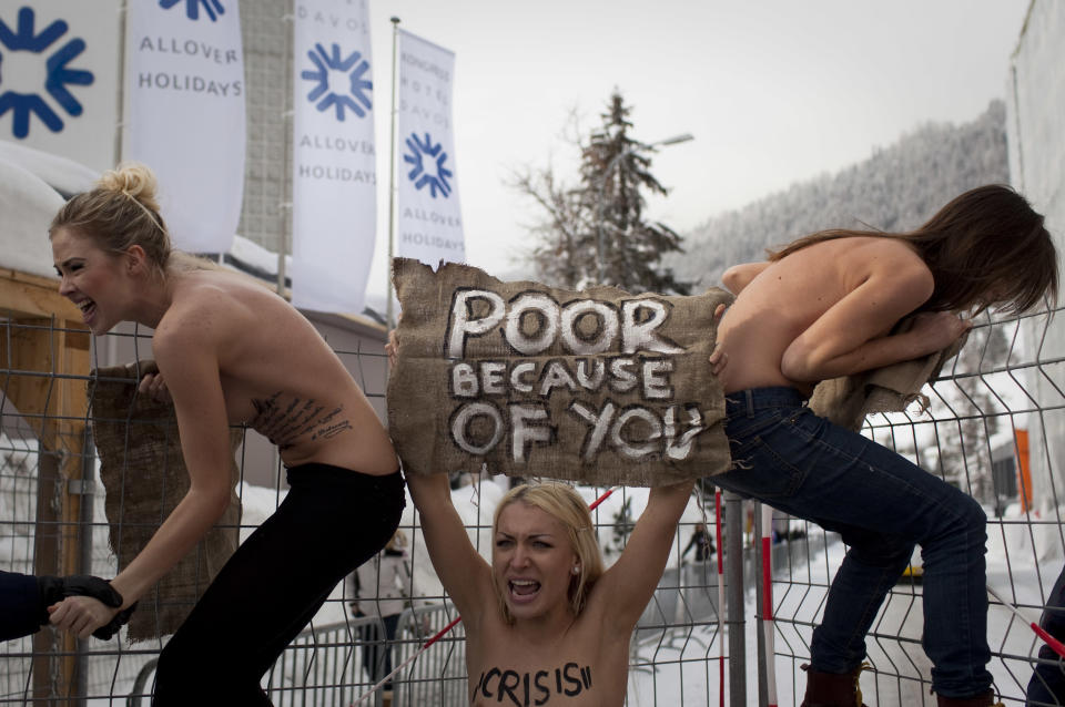 FILE - In this Saturday, Jan. 28, 2012 file photo made by Associated Press photographer Anja Niedringhaus, topless Ukrainian protesters climb up a fence at the entrance to the congress center where the World Economic Forum takes place in Davos, Switzerland. Niedringhaus, 48, an internationally acclaimed German photographer, was killed and an AP reporter was wounded on Friday, April 4, 2014 when an Afghan policeman opened fire while they were sitting in their car in eastern Afghanistan. (AP Photo/Anja Niedringhaus, File)