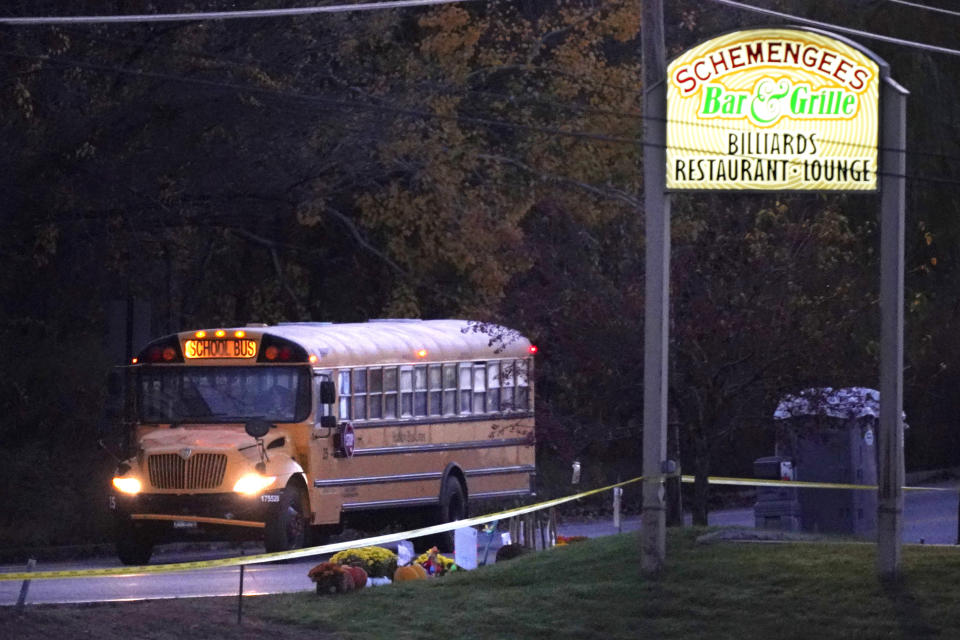 A school bus passes a makeshift memorial at Schemengees Bar and Grille, Tuesday, Oct. 31, 2023, the site of one of two mass shootings last week, in Lewiston, Maine. Classes resumed Tuesday in the wake of Maine's worst mass shooting. (AP Photo/Robert F. Bukaty)