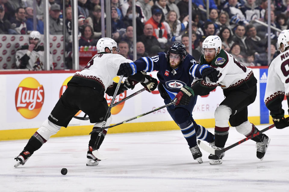 Winnipeg Jets' Pierre-Luc Dubois (80) skates through Arizona Coyotes' Patrik Nemeth (2) and Lawson Crouse (67) during the second period of an NHL hockey game, Tuesday, March 21, 2023 in Winnipeg, Manitoba. (Fred Greenslade/The Canadian Press via AP)