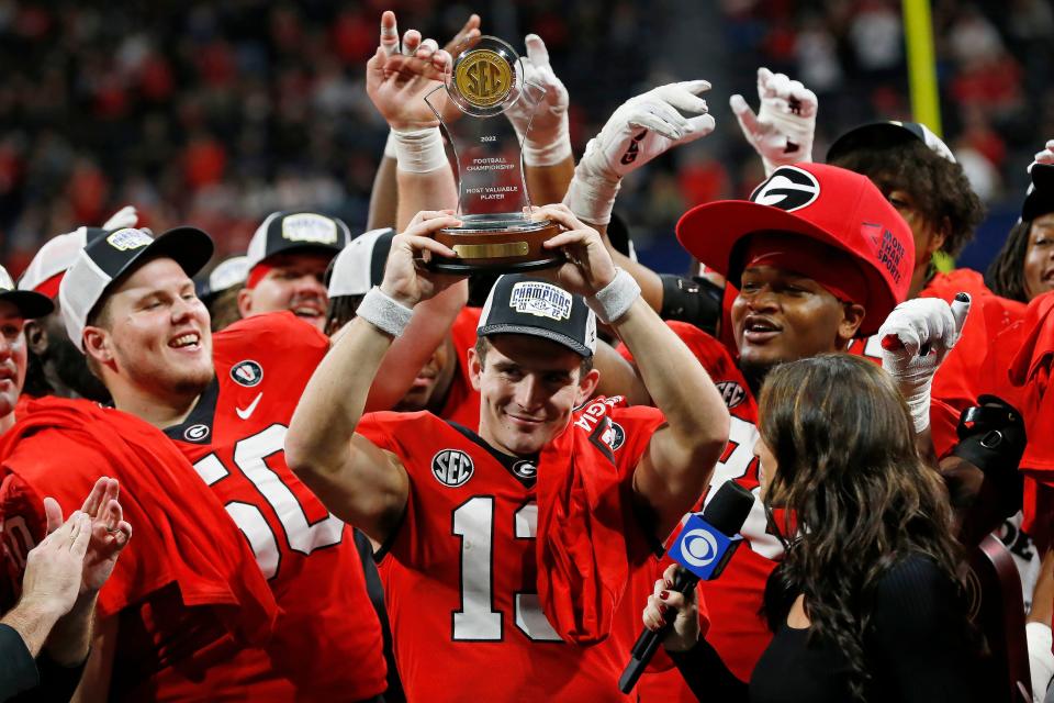 Georgia quarterback Stetson Bennett raises the SEC Championship MVP trophy after the Bulldogs' conference title game victory against LSU on Saturday. Georgia claimed the top seed in the final College Football Playoff rankings and will play Ohio State in the Peach Bowl for a berth in the national championship game.