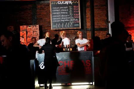 Bartenders wear wigs as they impersonate Republican presidential nominee Donald Trump while serving beers to revelers during a booze-up in Mexico City, Mexico, October 20, 2016. REUTERS/Carlos Jasso