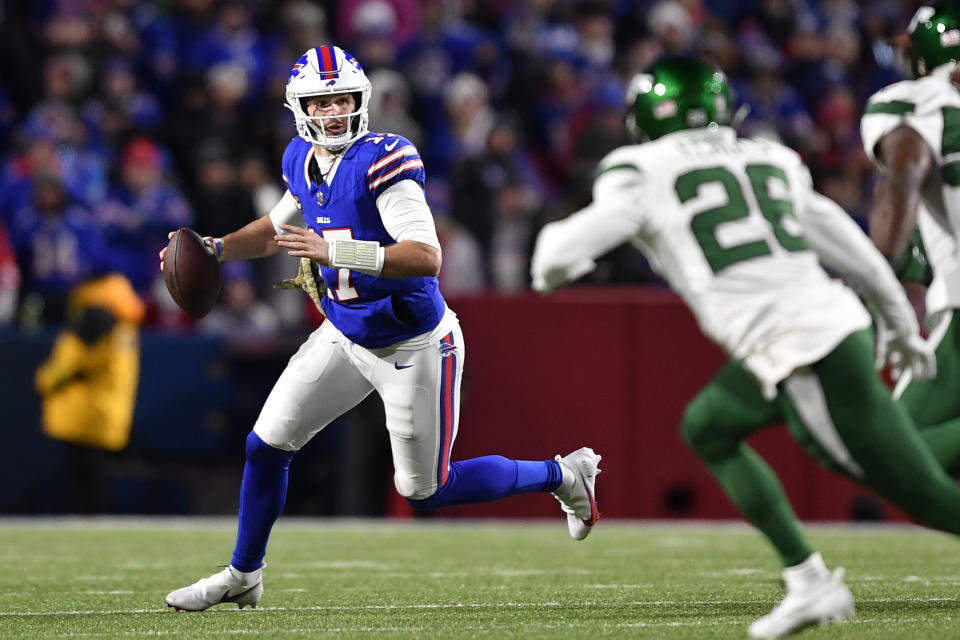 Buffalo Bills quarterback Josh Allen, left, rolls out looking to pass during the first half of an NFL football game against the New York Jets in Orchard Park, N.Y., Sunday, Nov. 19, 2023. (AP Photo/Adrian Kraus)
