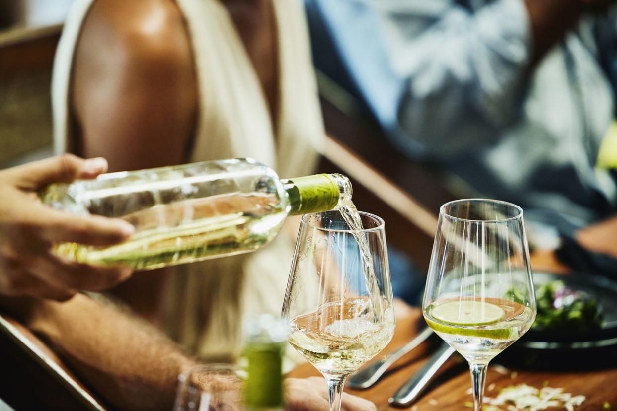 medium close up shot of man pouring wine into glass during wedding reception at tropical resort