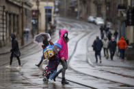 Many people wearing face masks as they move along a shopping street as rain falls in Nottingham, England, Tuesday Oct. 27, 2020. The Nottingham area will move into the Tier 3 highest level of coronavirus restrictions on upcoming Thursday because of a surge in COVID-19 cases. (Joe Giddens/PA via AP)