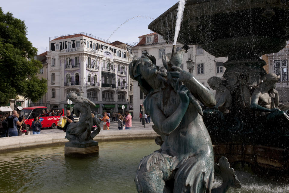 In this Sept. 28, 2012 photo, tourists take pictures by a fountain in Lisbon's central Rossio square. Portugal is scrapping its long-standing rent controls in one of the government's most radical economic and social reforms since the ailing country needed a euro 78 billion bailout last year, when it was engulfed by Europe's financial crisis. Critics say the anticipated rent hikes from next month could price thousands of families out of their homes. At the very least, the change aimed at boosting and modernizing the economy, will add to the financial burden on those struggling to cope with pay cuts and tax hikes designed to ease the country's crippling debt load. (AP Photo/Armando Franca)