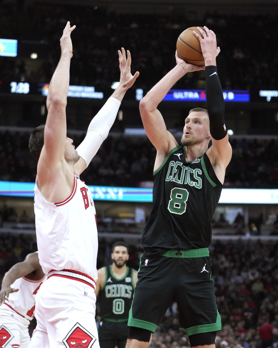 Boston Celtics' Kristaps Porzingis (8) shoots over Chicago Bulls' Nikola Vucevic, left, during the first half of an NBA basketball game Thursday, Feb. 22, 2024, in Chicago. (AP Photo/Charles Rex Arbogast)