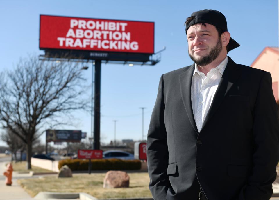 Anti-abortion activist Mark Lee Dickson stands in front of a “prohibit abortion trafficking” billboard, Jan. 16, 2024, in Amarillo. (Credit: Anne Rice/Avalanche-Journal)