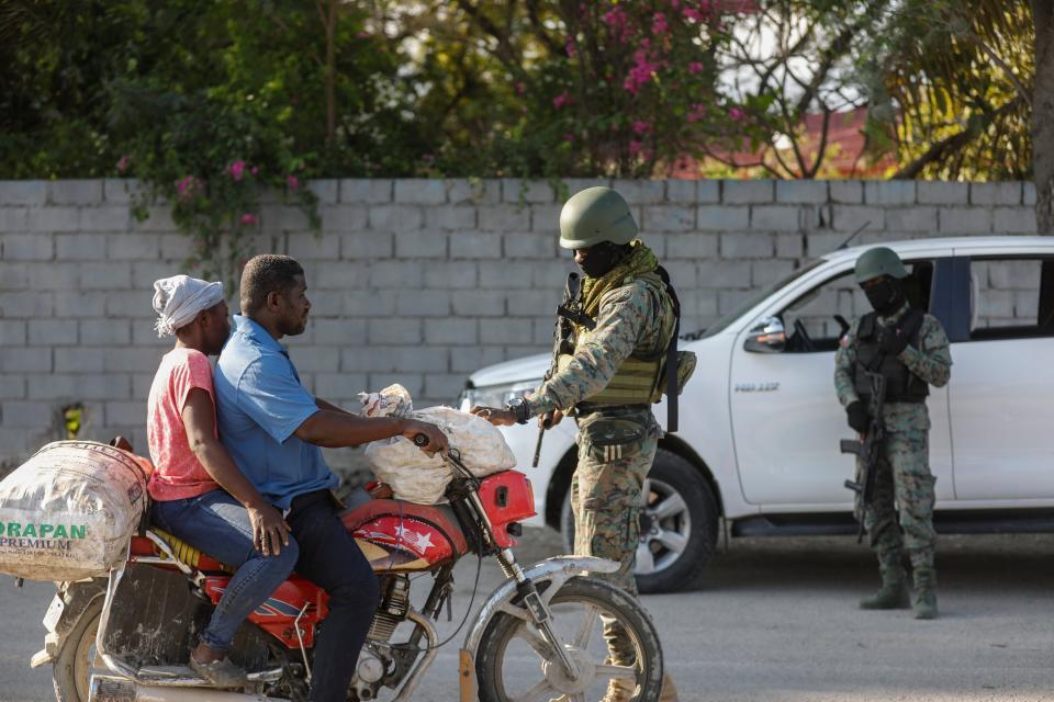 Soldiers inspect commuters at the entrance of the international airport in Port-au-Prince, Haiti, Wednesday, March 6, 2024. (AP Photo/Odelyn Joseph)