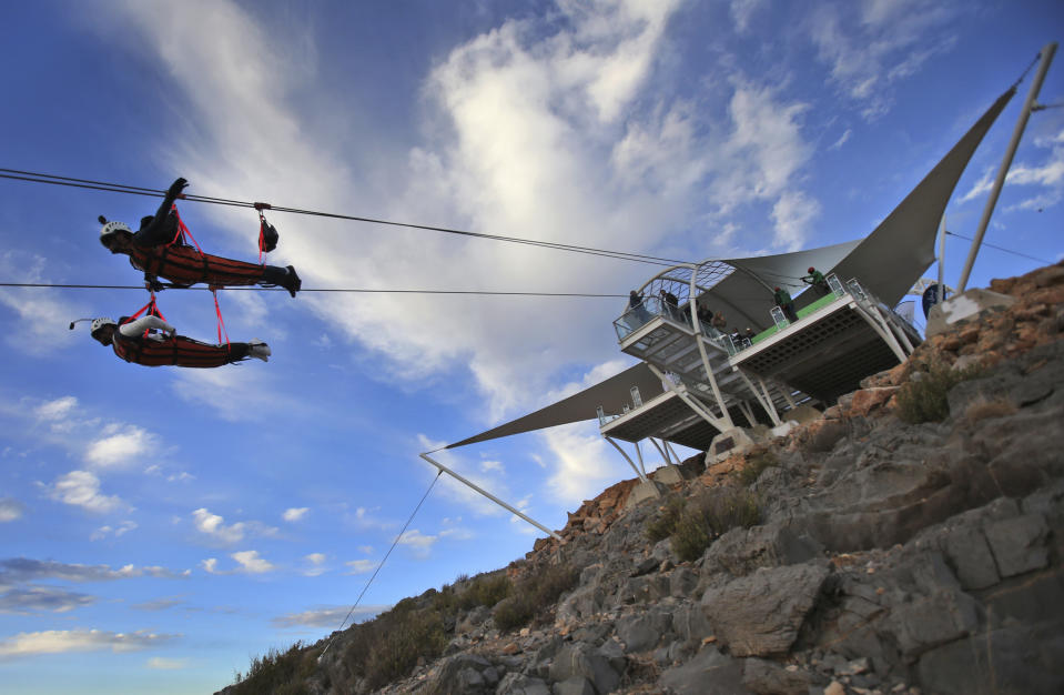 In this Wednesday, Jan. 31, 2018 photo, thrill-seekers ride fron the UAE's highest mountain as they try out a new zip line, on the peak of Jebel Jais mountain, 25 kms (15.5 miles) north east of Ras al-Khaimah, United Arab Emirates. The UAE is claiming a new world record with the opening of the world's longest zip line, measuring 2.83 kilometers (1.76 miles) in length. Guinness World Records officials certified the zip line on Thursday, the same day the attraction opened to the public. (AP Photo/Kamran Jebreili)