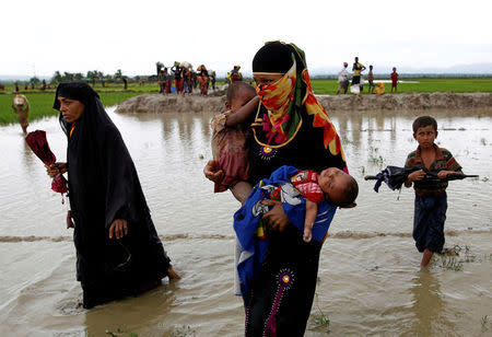 A Rohingya refugee woman carry children while walking in the water after travelling over the Bangladesh-Myanmar border in Teknaf, Bangladesh, September 1, 2017. REUTERS/Mohammad Ponir Hossain