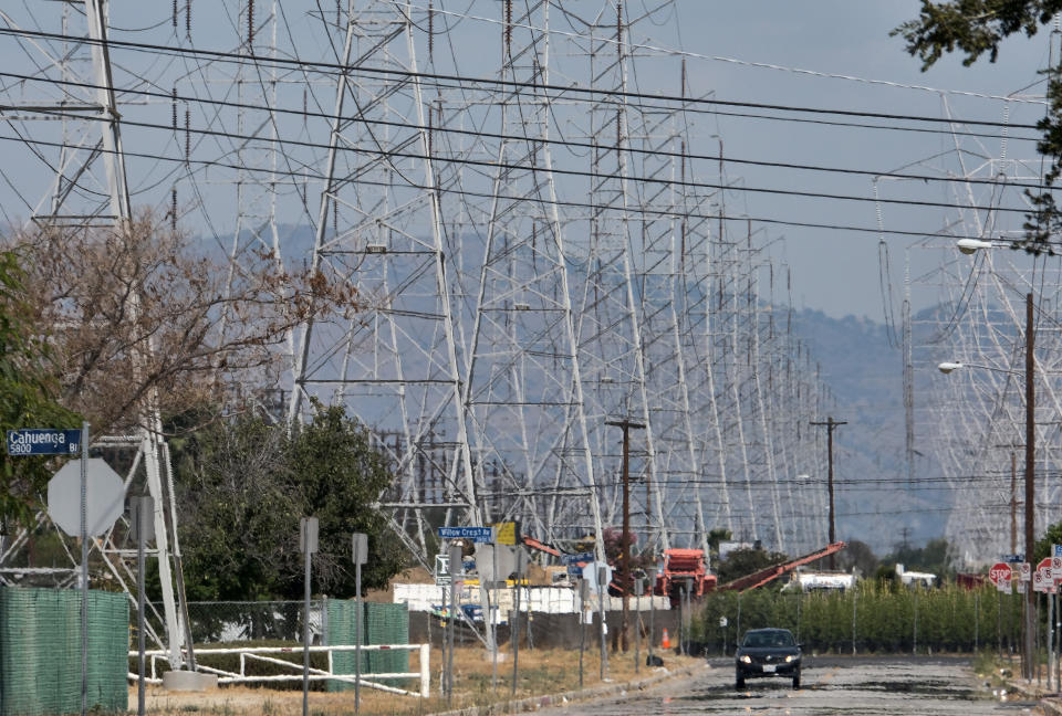 FILE - An automobile drives down a road as radiant heat is seen coming off of the pavement near high tension electrical lines in the North Hollywood section of Los Angeles on Aug. 15, 2020. On Wednesday, March 27, 2024, California regulators released a proposal that would change how utility bills are calculated. Regulators say this could help control price spikes during the hot summer months. (AP Photo/Richard Vogel,File)