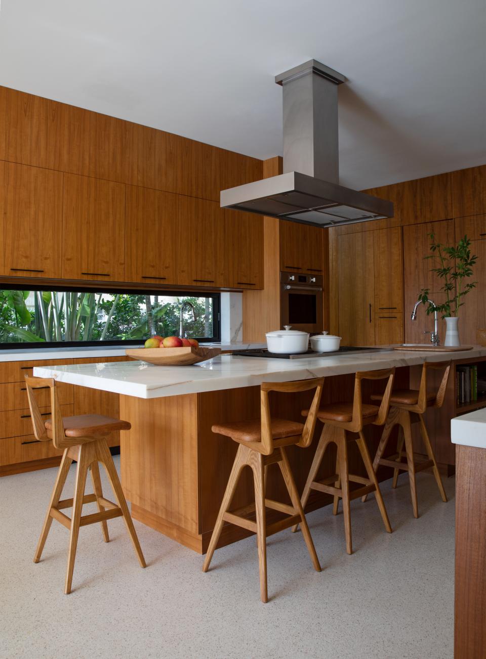 In the warm kitchen, the counter stools by TH Brown help to make the island even more functional, transforming it into a bar or breakfast table. The fruit bowl is from Odem Atelier.