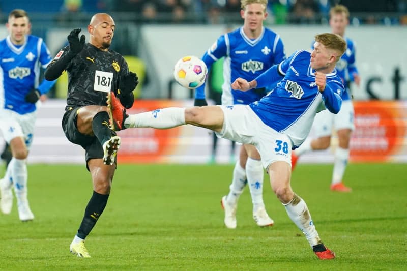 Dortmund's Donyell Malen (L) and Darmstadt's Clemens Riedel battle for the ball during the German Bundesliga soccer match between Darmstadt 98 and Borussia Dortmund at Merck Stadium. Uwe Anspach/dpa