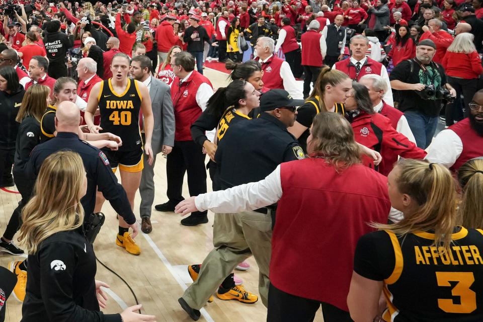 Jan 21, 2024; Columbus, Ohio, USA; Iowa Hawkeyes guard Caitlin Clark (22) is helped off by security as fans storm the court following the NCAA women’s basketball game against the Ohio State Buckeyes at Value City Arena. Ohio State won 100-92.