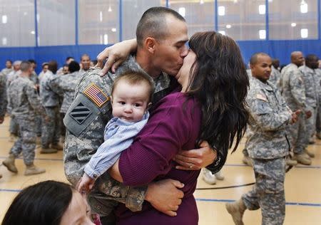 Staff Sgt. Keith Fidler kisses his wife Cynthia, as their son Kolin looks on, during a homecoming ceremony in New York, April 8, 2011 for the New York Army National Guard's 442nd Military Police Company's return from Iraq. REUTERS/Shannon Stapleton