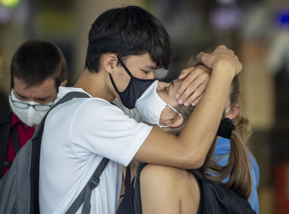 FILE - A young couple with face masks kisses goodbye at the airport in Frankfurt, Germany, Aug. 3, 2020. Germany is set to mark 100,000 deaths from COVID-19 this week, passing a somber milestone that several of its neighbors crossed months ago but which some in Western Europe's most populous nation had hoped to avoid. (AP Photo/Michael Probst, File)