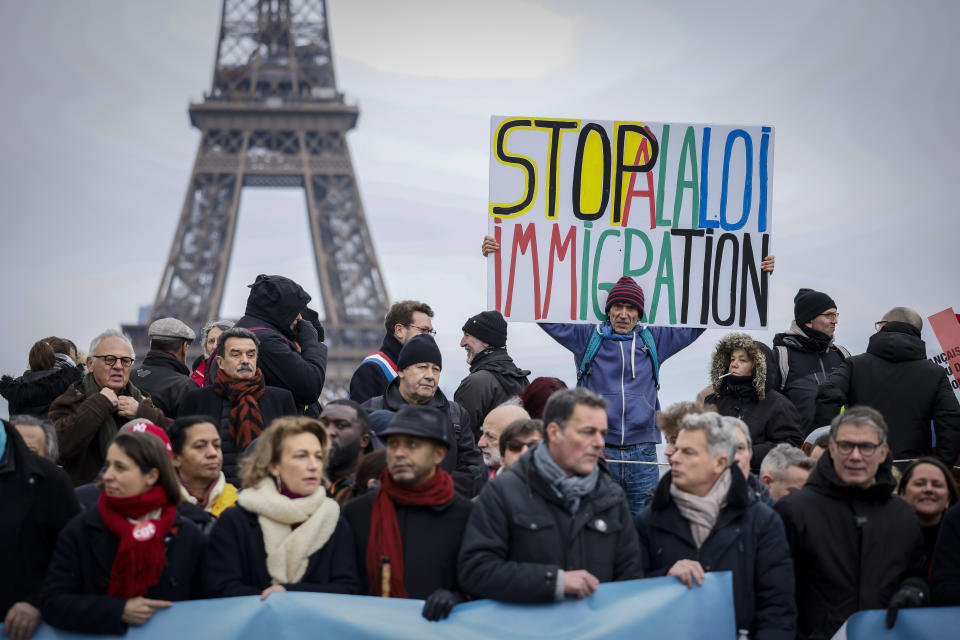 An opponent of France's immigration law holds a placard that reads, "stop to the immigration law" at Trocadero Plaza near Eiffel Tower during a protest in Paris, Sunday, Jan. 21, 2024. The Constitutional Council is reviewing next week the government's controversial immigration law, to check that measures is in line with the Constitution. (AP Photo/Thomas Padilla)