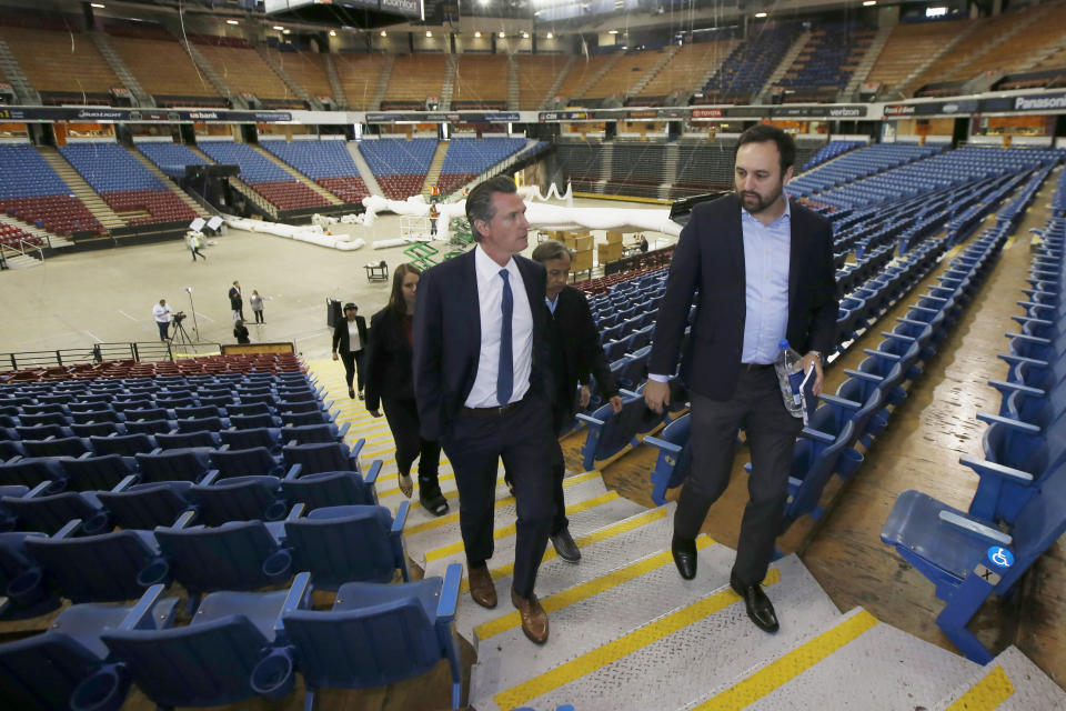 FILE — In this April 6, 2020, file photo, California Gov. Gavin Newsom, left, accompanied by Jason Kenney, deputy director of the Real Estate Services Division of the Department of General Services, tours Sleep Train Arena while it was being transformed into a 400-bed emergency field hospital in Sacramento, Calif. California spent nearly $200 million to set up, operate and staff alternate care sites that ultimately provided little help when the state’s worst coronavirus surge spiraled out of control last winter, forcing exhausted hospital workers to treat patients in tents and cafeterias. (AP Photo/Rich Pedroncelli, Pool, File)