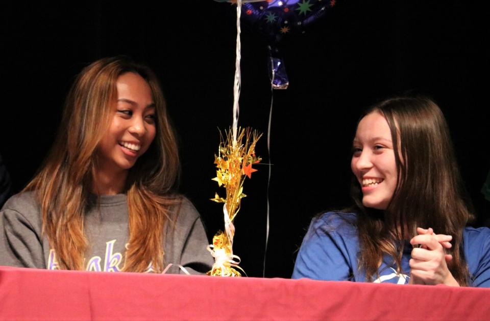 South Kitsap dance team member Jiselle Javier (left) laughs with basketball player Aly Loudermilk during Monday's college signing event at South Kitsap High School.