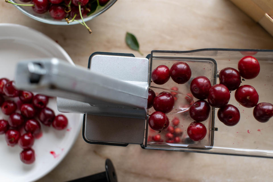 cherries being pitted with a cherry pitter