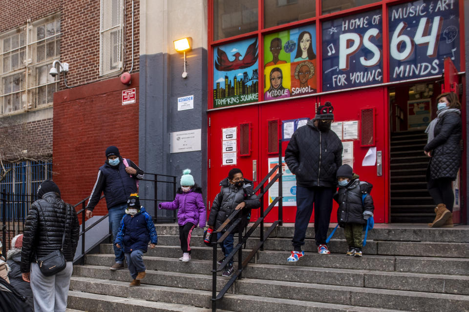 Parents pick up their children while wearing masks outside of P.S. 64 in the East Village neighborhood of Manhattan, Tuesday, Dec. 21, 2021, in New York. (AP Photo/Brittainy Newman)
