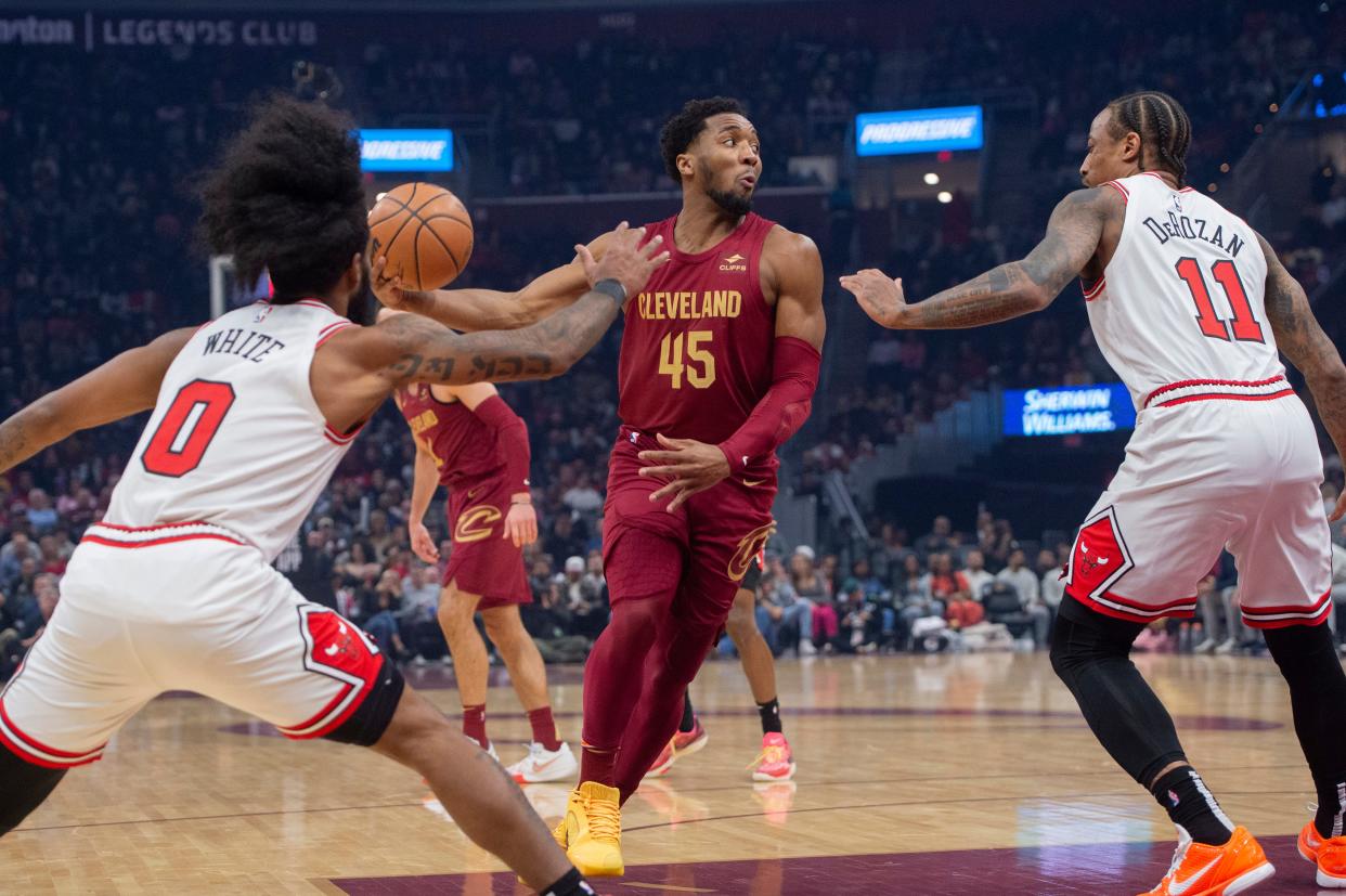 Cleveland Cavaliers' Donovan Mitchell (45) looks to pass as Chicago Bulls' Coby White (0) and DeMar DeRozan (11) defend during the first half of an NBA basketball game in Cleveland, Wednesday, Feb. 14, 2024. (AP Photo/Phil Long)