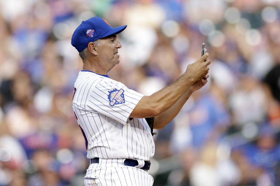 Former New York Mets pitcher John Franco takes a photo with his phone before throwing the first pitch during an Old-Timers' game before a baseball game between the Colorado Rockies and the Mets, Saturday, Aug. 27, 2022, in New York. (AP Photo/Adam Hunger)