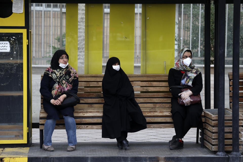 People wearing protective face masks to help prevent the spread of the coronavirus sit at a bus stop in the city of Zanjan, some 330 kilometers (205 miles) west of the capital Tehran, Iran, Sunday, July 5, 2020. Iran on Sunday instituted mandatory mask-wearing as fears mount over newly spiking reported deaths from the coronavirus, even as its public increasingly shrugs off the danger of the COVID-19 illness it causes. (AP Photo Vahid Salemi)