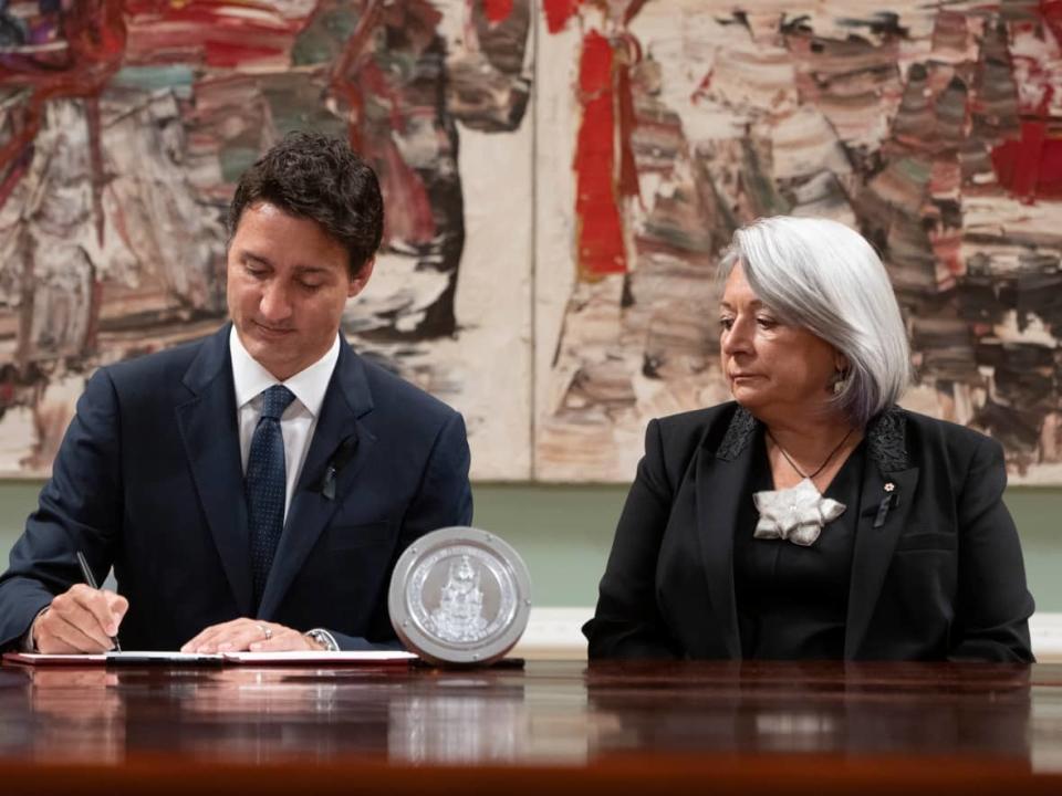 Simon looks on as Trudeau signs documents during the accession ceremony on Saturday. (Adrian Wyld/The Canadian Press - image credit)