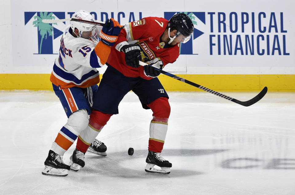 New York Islanders right wing Cal Clutterbuck (15) battles Florida Panthers defenseman Dmitry Kulikov (7) for the puck during the first period of an NHL hockey game, Saturday, Dec. 2, 2023, in Sunrise, Fla. (AP Photo/Michael Laughlin)