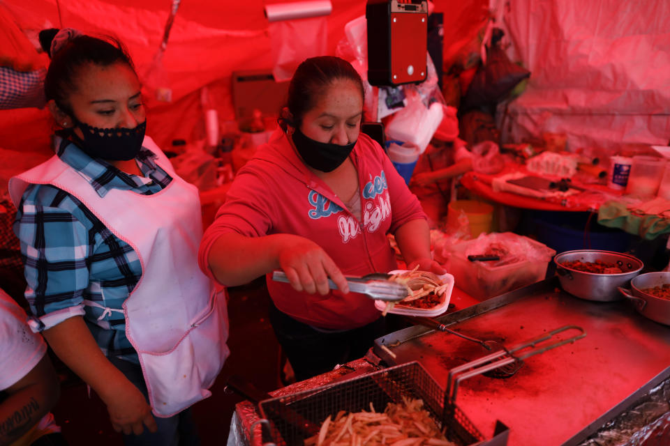 A vendor serves up tacos on disposable plates, at a street stand in central Mexico City, Friday, Jan. 1, 2021. The few street food vendors out working on New Year's Day amid the COVID-19 pandemic said they were either unaware of or were still figuring out how to comply with a broad ban on single-use containers, forks, straws, and other ubiquitous items that took effect Friday in Mexico's capital, one of the world's largest cities, after more than a year of preparation. (AP Photo/Rebecca Blackwell)