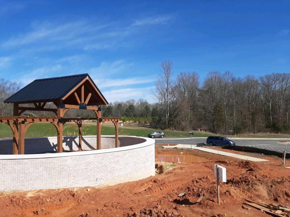 Drivers ride past an entry monument under construction for the Elizabeth neighborhood in Fort Mill. In the distance, a small sign notes where new apartments are planned.