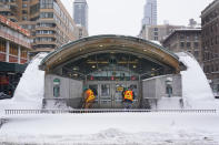 People work to clear snow from the entrance of a subway station following a winter storm in Manhattan, New York, Tuesday, Feb. 2, 2021. (AP Photo/Seth Wenig)