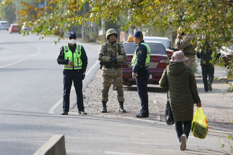 Traffic police officers and members of Kyrgyz armed forces stand guard in the street in Bishkek