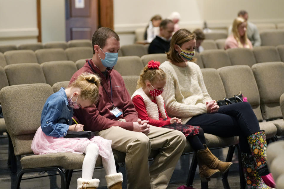 Jonathan Vaughn, second from left, and his family, Addison, 5, left, Ann Marie, 7, second from right, and wife Alesha Vaughn pray during services in the Worship Center at Highland Colony Baptist Church in Ridgeland, Miss., Nov. 29, 2020. The church practices covid protocols by allowing families to sit spaced out from others, separating older and more vulnerable members in the worship hall and providing sanitizer and masks at the entrance. (AP Photo/Rogelio V. Solis)