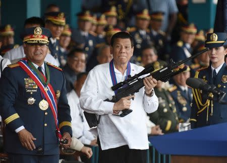 Philippine President Rodrigo Duterte holds a Galil sniper rifle next to outgoing National Police Chief Ronald Bato Dela Rosa during a handover ceremony in Camp Crame, Quezon City, Manila, Philippines, April 19, 2018. REUTERS/Dondi Tawatao/Files