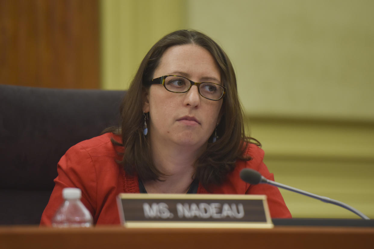 Brianne Nadeau listens at the microphone with a nameplate in front of her saying: Ms. Nadeau.