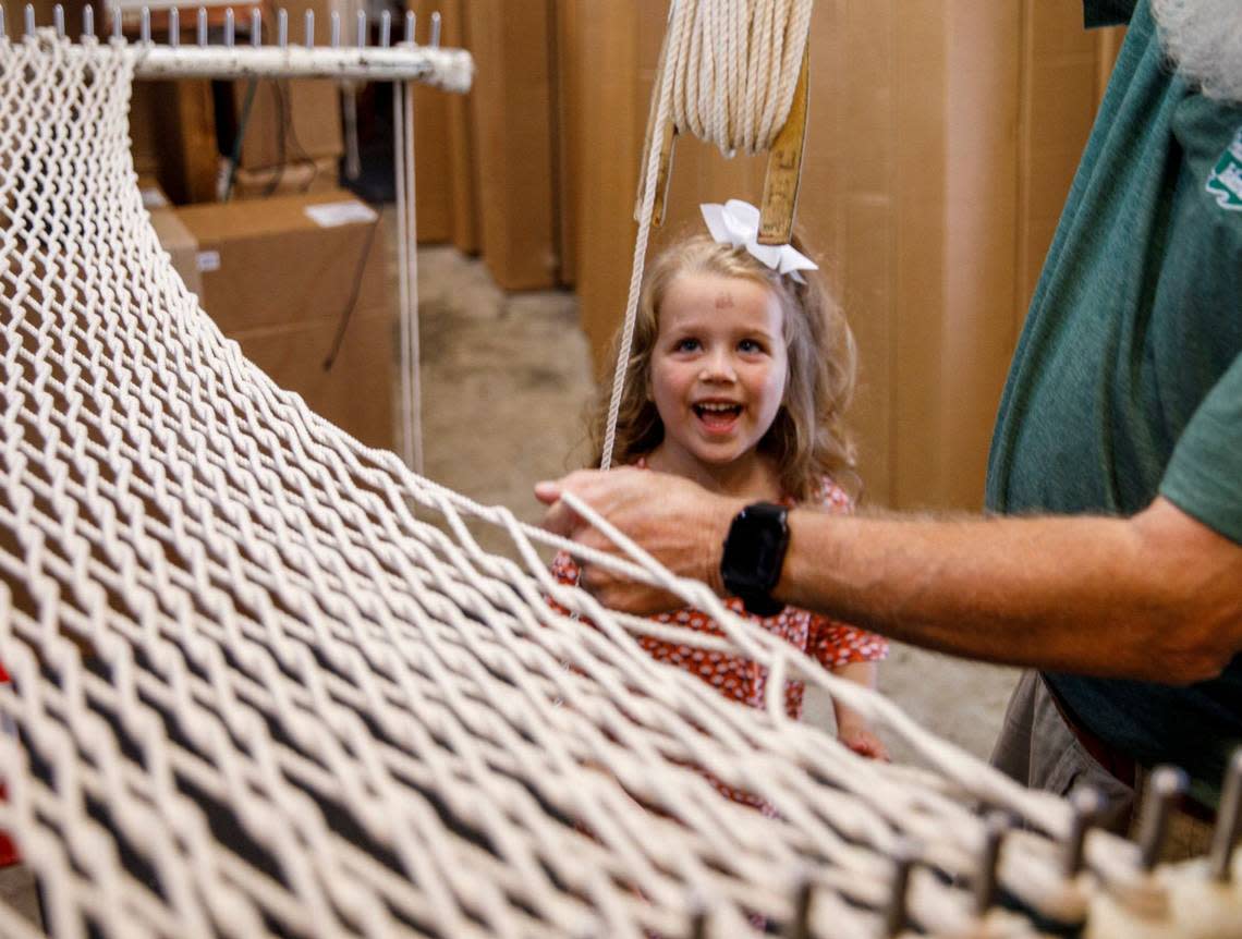 Mary Clare Rushing of Atlanta, Georgia watches as Harry Woodbury, a hammock maker of 25 years, weaves a Pawleys Island hammock from 1300 feet of rope. The Pawleys Island Original Hammock Shop opened in 1935 by the family of riverboat captain Joshua John Ward who pioneered the use of spreader bars for rope hammocks. Aug. 30, 2024.