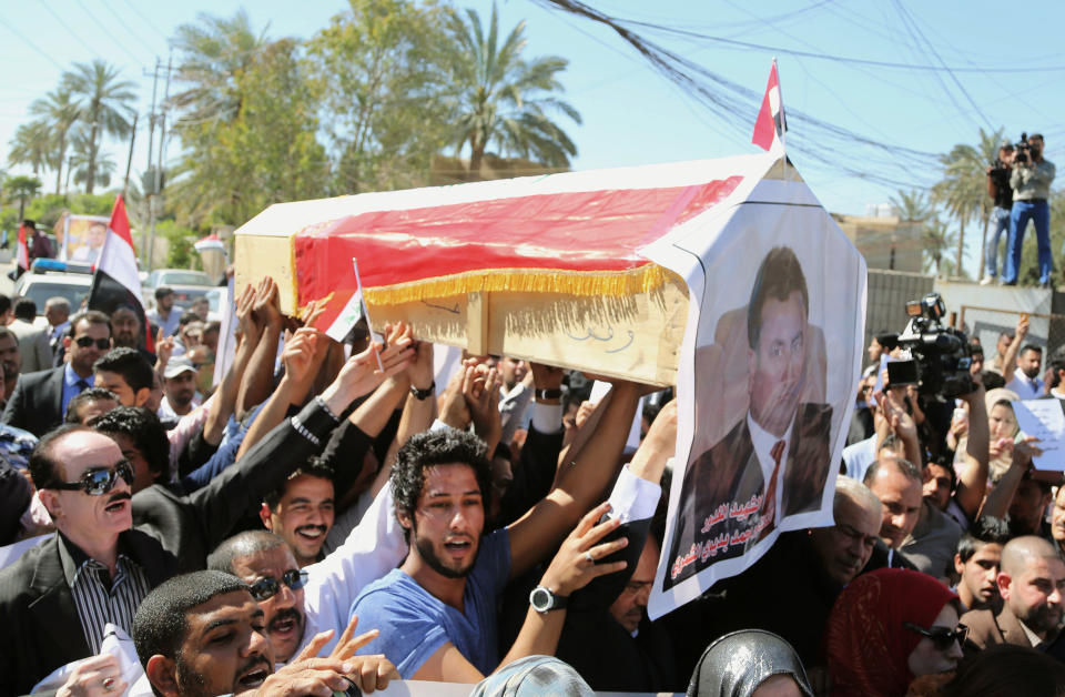 Mourners chant slogans during a symbolic funeral for the bureau chief of a local radio station in Baghdad, Iraq, Sunday, March 23, 2014. A junior officer working for Iraqi President Jalal Talabani, also an ethnic Kurd, shot dead Mohammed Bdaiwi, in the poster, a well-known radio journalist during a quarrel Saturday near the leader's east Baghdad residence, police said. (AP Photo/Karim Kadim)